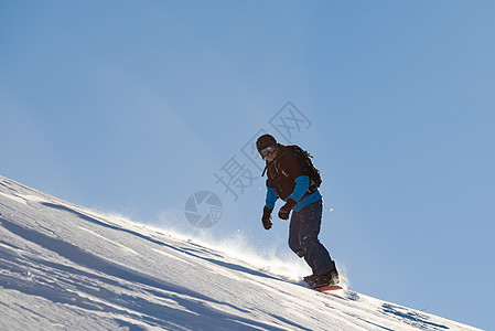 滑雪运动员在太阳尼日登上山峰红雪板 滑雪和冬季运动娱乐单板晴天粉末男人旅行下坡活动行动头盔图片