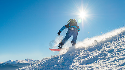 滑雪运动员在太阳尼日登上山峰的雪板 滑雪和冬季运动粉末风镜头盔假期娱乐行动活动速度单板乐趣图片