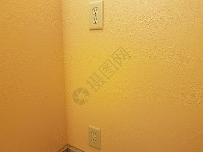 橙色或黄色涂漆墙壁上的电插口图片