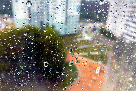 灰色的城市背景下有大雨滴的窗户 第一场夏季风暴 特写 窗玻璃上的雨滴大而详细 有选择的焦点图片