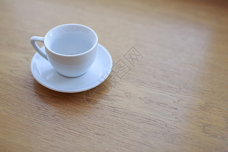 午后阳光下 一张木桌上放着一个没有饮料的纯白色陶瓷杯碟办公室小路杯子剪裁木头盘子食物咖啡早餐咖啡店图片