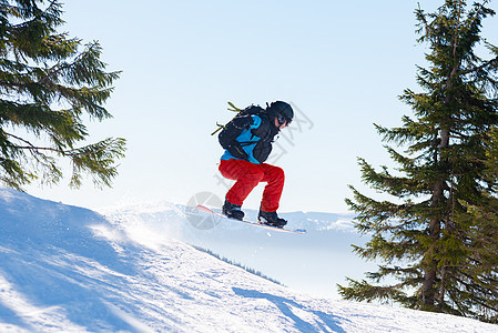 滑雪运动员在太阳尼日跳上山中红雪板 滑雪和冬季运动蓝色旅行男人下坡速度单板头盔季节天空行动图片
