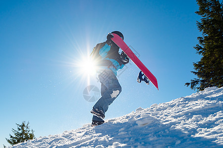 滑雪运动员在太阳尼日与红雪板一起爬上山中山顶 滑雪和冬季运动滑雪板季节头盔乐趣粉末旅行行动娱乐假期活动图片