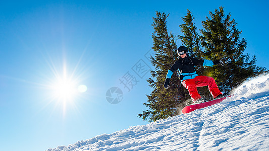 单板滑雪滑雪运动员在太阳尼日登上山峰红雪板 滑雪和冬季运动旅行乐趣下坡蓝色假期滑雪板活动娱乐季节单板背景