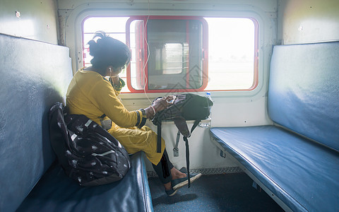 在旅客列车上独自旅行时使用手机的女人 旅行者在日常生活和旅行中享受现代技术 特写肖像年轻的成年女士印度种族互联网商务旅游媒体背包图片