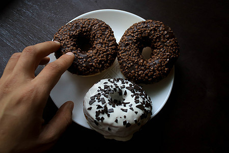 三个甜甜圈在白色盘子上 棕色背景生日桌子早餐蛋糕磨砂面包飞碟面团食物巧克力图片