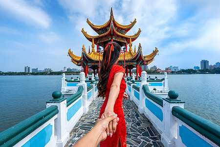 女性观光客握着男人的手 带领他前往台湾高雄著名的旅游景点旗袍女士宗教传统宝塔建筑寺庙裙子吸引力城市图片
