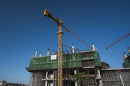 蓝天的起重机和建筑工地 未完工建筑的金属结构施工 塔式起重机用于建造多仓库建筑城市机器公寓水泥高楼工作财产房子商业天空图片