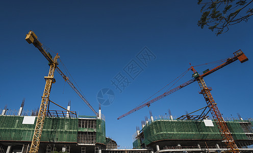 蓝天的起重机和建筑工地 未完工建筑的金属结构施工 塔式起重机用于建造多仓库建筑项目公寓住宅生长财产机器框架商业建筑学技术图片