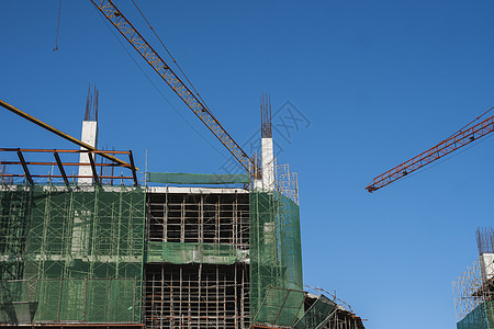 蓝天的起重机和建筑工地 未完工建筑的金属结构施工 塔式起重机用于建造多仓库建筑技术住宅财产脚手架高楼城市摩天大楼建筑学工程商业图片