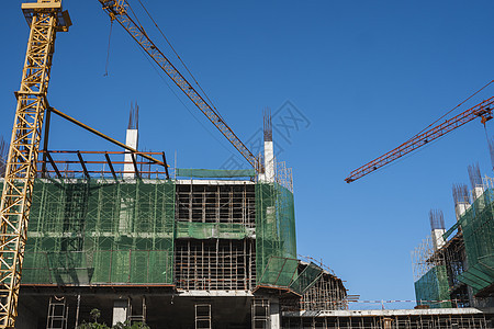 蓝天的起重机和建筑工地 未完工建筑的金属结构施工 塔式起重机用于建造多仓库建筑工程项目蓝色城市生长公寓框架商业工作天空图片