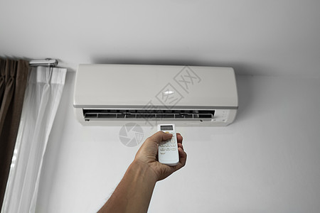 使用遥控器的人的手 手持 rc 和调节安装在白墙上的空调温度 室内舒适温度 健康理念和节能手臂微风冷却器活力护发素加湿器扇子净化图片