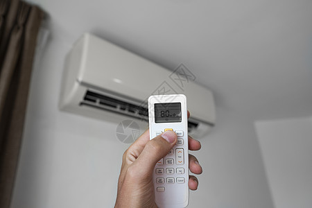 使用遥控器的人的手 手持 rc 和调节安装在白墙上的空调温度 室内舒适温度 健康理念和节能手臂加湿器微风按钮冷却器扇子活力气候技图片