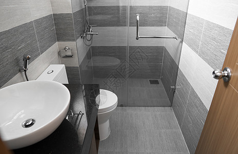 在现代浴室里有玻璃墙和门的淋浴小屋洗手间卫生毛巾玻璃瓷砖墙淋浴间房子脸盆家庭家具背景图片