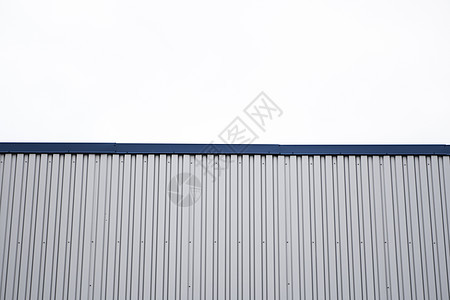 带有蓝色金属角的建筑物上的金属波纹板 工厂和工业建筑上多云天空背景下的白色铝金属波纹屋顶或墙板盘子屋顶材料镀锌床单房子建筑学仓库图片
