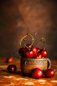 橙色背景的古老陶瓷杯中新鲜樱桃莓图片