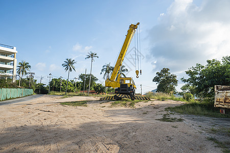 有上升的伸缩臂的黄色汽车起重机在户外 建筑工地上的移动式建筑起重机 起重机在施工大楼下等待工作 重工业机壳蓝色光束地面升降机天空图片