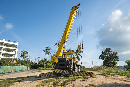 有上升的伸缩臂的黄色汽车起重机在户外 建筑工地上的移动式建筑起重机 起重机在施工大楼下等待工作 重工业机壳运输容量蓝色活动升降机背景图片