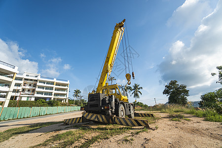 有上升的伸缩臂的黄色汽车起重机在户外 建筑工地上的移动式建筑起重机 起重机在施工大楼下等待工作 重工业机械卡车车辆勃起力量机器装图片