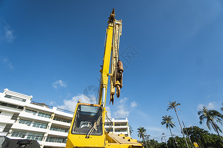 有上升的伸缩臂的黄色汽车起重机在户外 建筑工地上的移动式建筑起重机 起重机在施工大楼下等待工作 重工业运输绳索柴油机活动地面天空图片