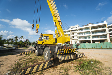 有上升的伸缩臂的黄色汽车起重机在户外 建筑工地上的移动式建筑起重机 起重机在施工大楼下等待工作 重工业绳索活动升降机运输地面勃起图片