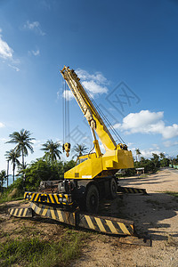 有上升的伸缩臂的黄色汽车起重机在户外 建筑工地上的移动式建筑起重机 起重机在施工大楼下等待工作 重工业卡车绳索蓝色活动运输柴油机图片