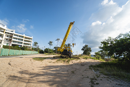 有上升的伸缩臂的黄色汽车起重机在户外 建筑工地上的移动式建筑起重机 起重机在施工大楼下等待工作 重工业技术升降机机械繁荣力量活动图片