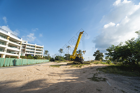 有上升的伸缩臂的黄色汽车起重机在户外 建筑工地上的移动式建筑起重机 起重机在施工大楼下等待工作 重工业活动蓝色升降机光束技术运输图片