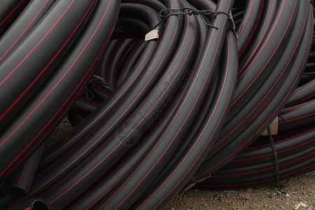 带有红线的黑色橡胶或塑料管作为建筑工地的建筑材料和设备 用作水管材料下水道工人技术软管蓝色车辆管道管子住房图片