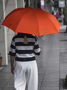 背对着女人的眼神 带着橙色雨伞在街上行走快乐幸福雨衣生活街道微笑城市天气胡同沉思图片