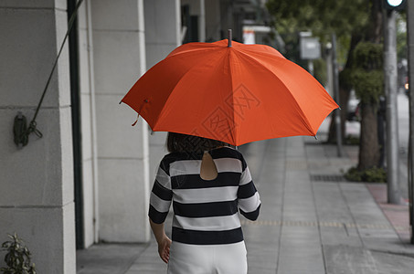 背对着女人的眼神 带着橙色雨伞在街上行走成人乐趣快乐女孩外套女性胡同天气公园街道图片