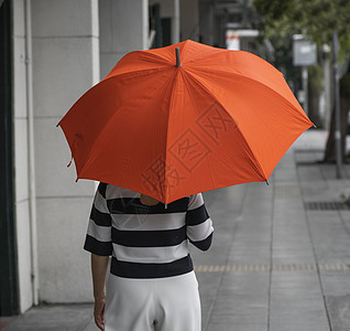 背对着女人的眼神 带着橙色雨伞在街上行走沉思季节幸福下雨外套街道女性女士胡同女孩图片