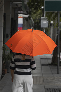 背对着女人的眼神 带着橙色雨伞在街上行走雨衣成人幸福外套季节胡同快乐女孩街道女性图片