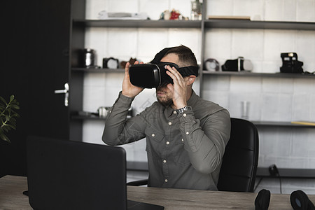 困惑或悲伤的留着胡子的年轻男子戴着虚拟现实眼镜坐在电脑前 现代技术 未来技术的概念白色成人男人享受风镜展示眼镜工作室胡须耳机图片