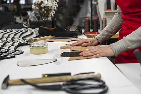 鞋匠正在用刷子在一些将用于制鞋的皮革上涂胶 鞋匠正在他的工作室的桌子上工作作坊机械男性生产男人服务皮匠维修工具鞋类图片