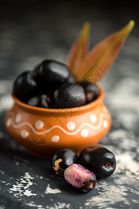 Jambolan 梅花或果酱或果子 爪哇梅和石质本底叶叶食物水果种子石头篮子药物植物叶子纹理紫色图片