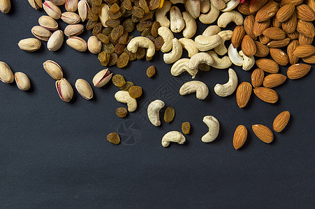 深色背景的健康混合干果和坚果 Almonds Pistachio 腰果 Raisins情调食物种子开心果饮食诱惑花生脱水水果浆果图片