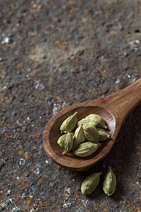 纸质背景的木勺中的卡达莫舱食物草本植物茴香香料小豆蔻药品香味豆蔻厨房植物图片