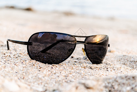 沙子上的太阳镜 反映海上日落和摄影师背景图片