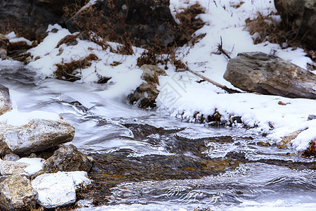 一条小溪流在冰薄的岩石中流淌森林美丽石头绿色运动瀑布白色流动公园溪流图片