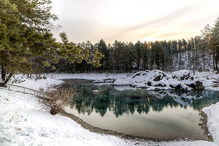冬季山地湖和树木之间的山岭天空森林蓝色池塘木头季节天气日落反射全景背景图片