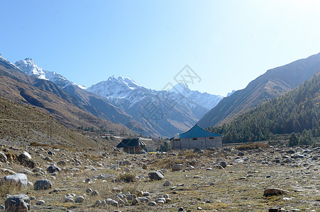 喜马拉雅山脉高山上的山间小屋 为登山者 登山者和徒步旅行者提供庇护所 背景是互锁重叠的小山脊 V 形山谷房子旅游峡谷活动衬套雪山图片