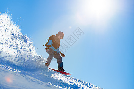 滑雪者骑着红雪板在亮太阳山区的斜坡上 滑雪和冬季运动概念速度活动季节旅行太阳娱乐假期蓝色背包滑雪板图片