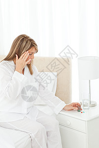 女人在床上头痛的头痛祸根疾病打扰成人药品医疗不便女性白色女士图片