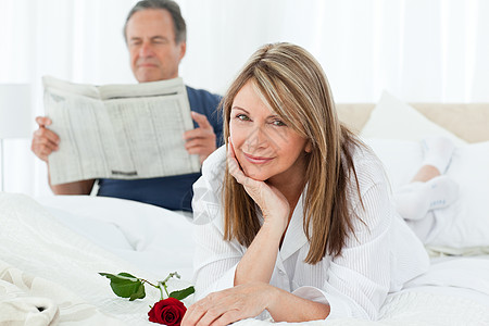幸福的女人带着玫瑰 而她的丈夫正在看报纸妻子已婚沙发房子微笑投标拥抱女士长椅夫妻图片