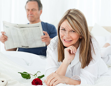幸福的女人带着玫瑰 而她的丈夫正在看报纸女士妻子房子惊喜香味生日投标长椅微笑拥抱图片
