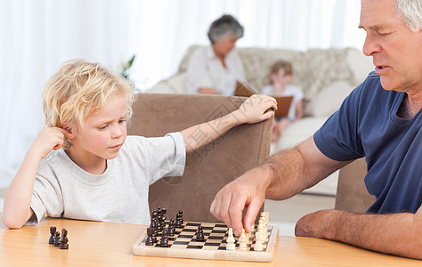 年轻男孩和爷爷下象棋了乐趣家庭祖父长椅男生老年游戏孩子房间青春期图片