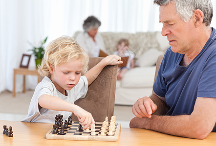 年轻男孩和爷爷下象棋了游戏木板沙发老年家庭祖父退休长椅青春期房间图片