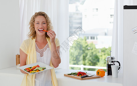 美丽的女人在吃蔬菜啊平底锅勺子火炉女士母亲女性青年厨房美食女孩图片
