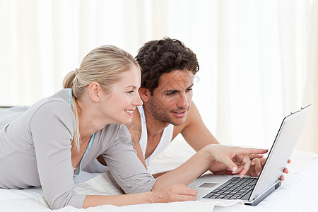 可爱的一对情侣在床上看笔记本电脑互联网男朋友微笑技术女朋友女孩卧室夫妻情人男性图片
